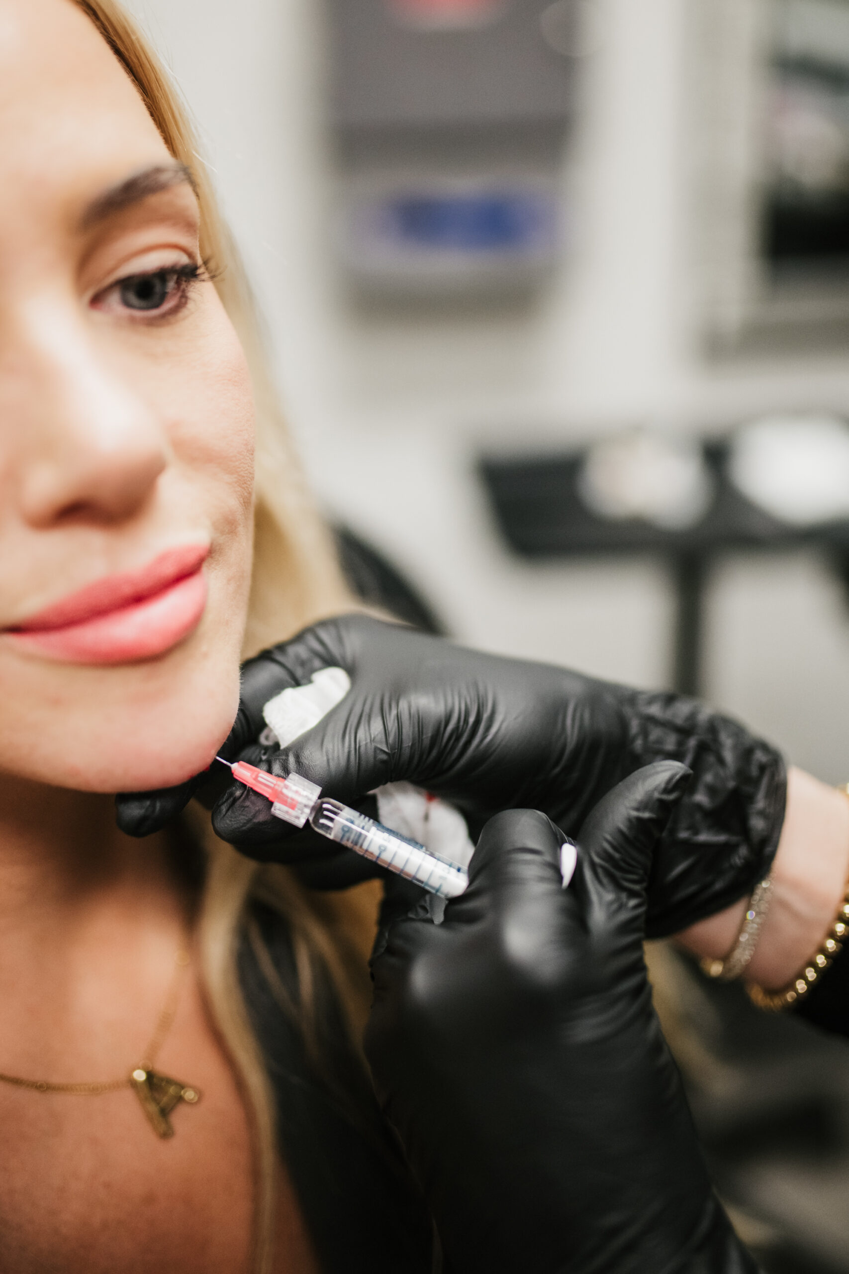 You see the hands of a nurse practitioner injecting filler into a client's chin